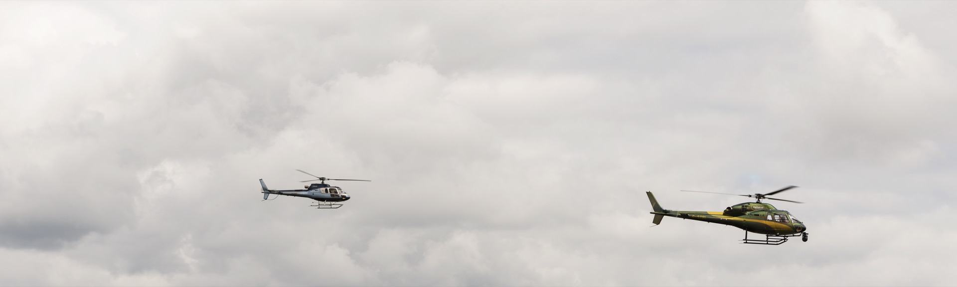 Two private helicopters flying through clouds, business helicopter travel